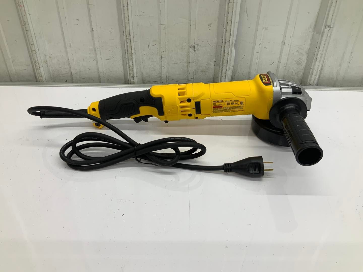 A yellow and black grinder is sitting on a white table.