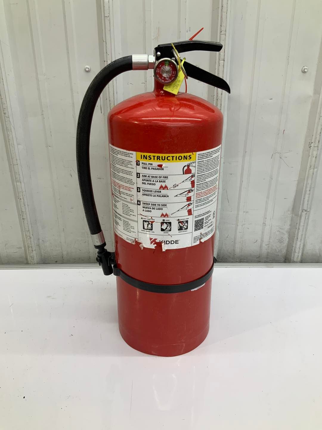 A red fire extinguisher is sitting on a white table.