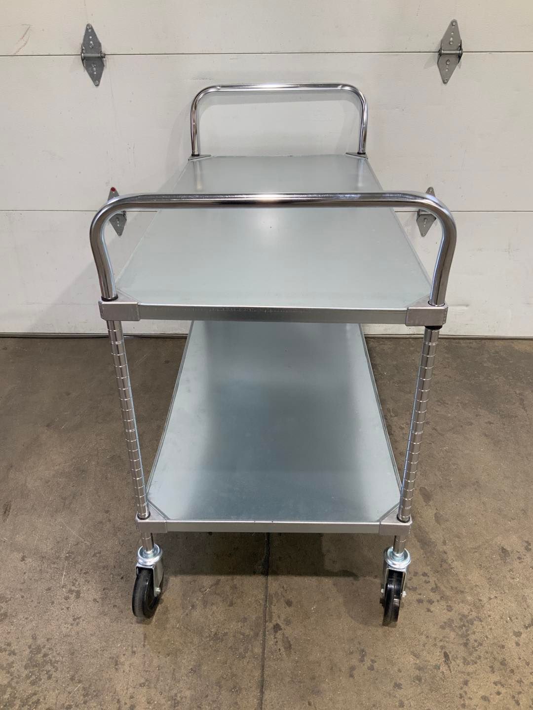 A stainless steel cart with wheels is sitting in front of a garage door.