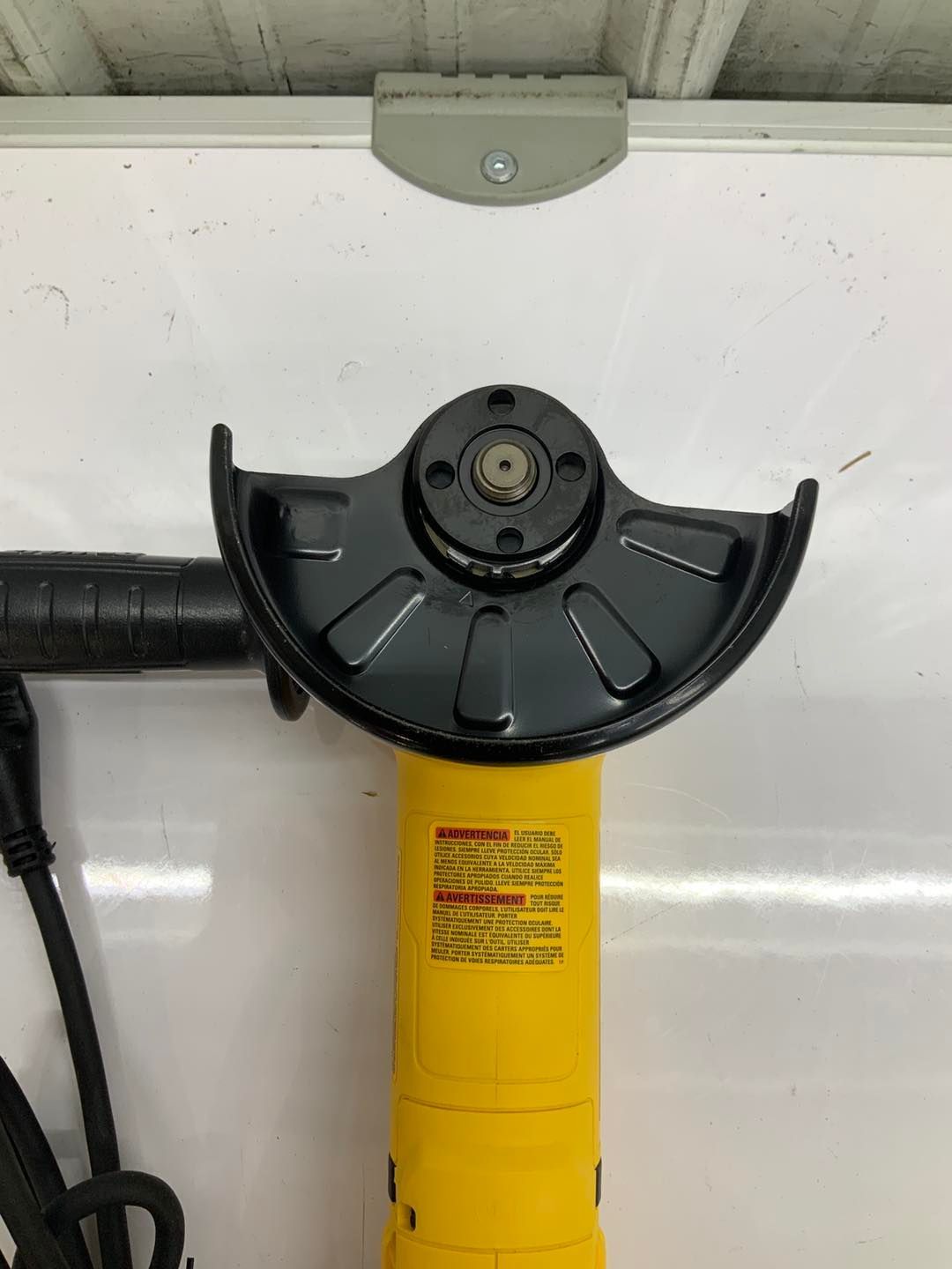 A yellow and black angle grinder is sitting on top of a white board.