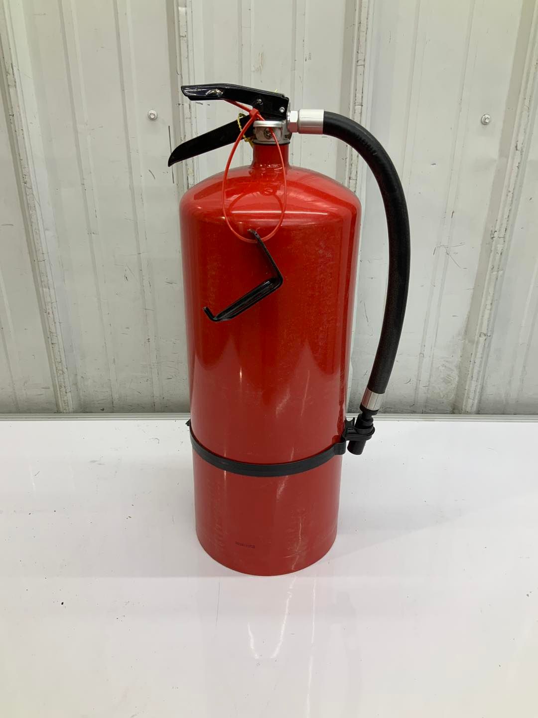 A red fire extinguisher is sitting on a white table.