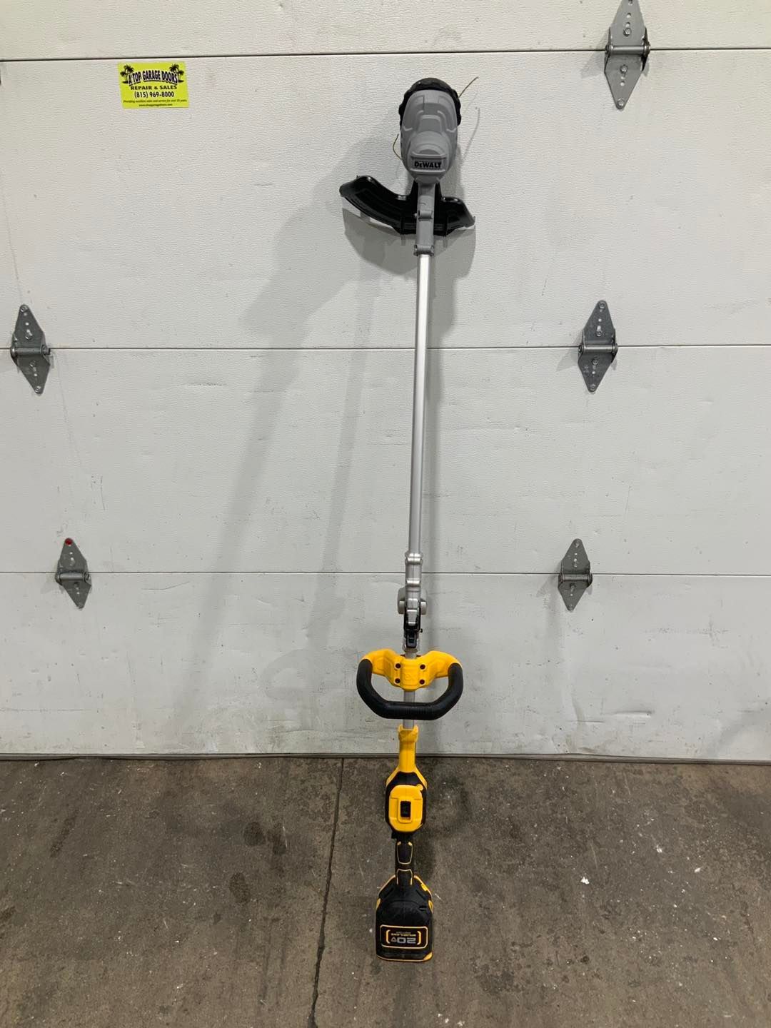 A lawn mower is sitting in front of a garage door.
