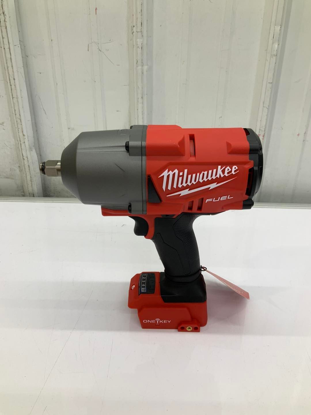 A milwaukee cordless impact wrench is sitting on a white table.