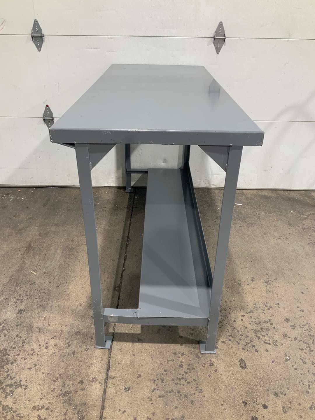 A gray metal table is sitting on a concrete floor in front of a garage door.