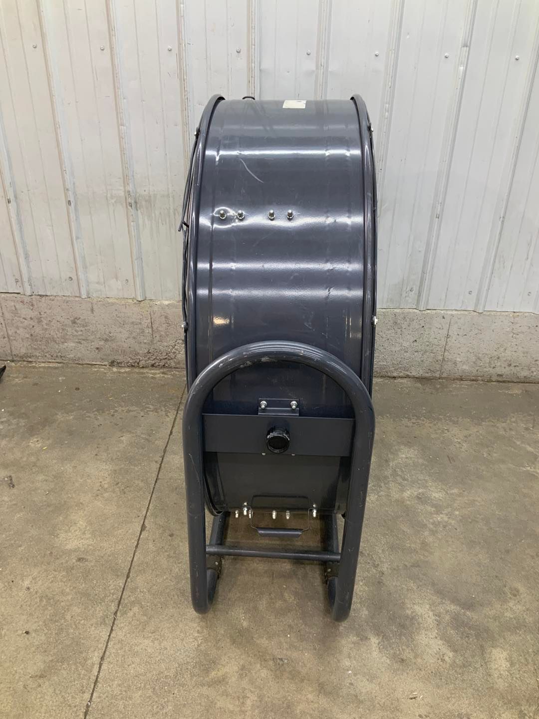 A large fan is sitting on the ground in front of a white wall.