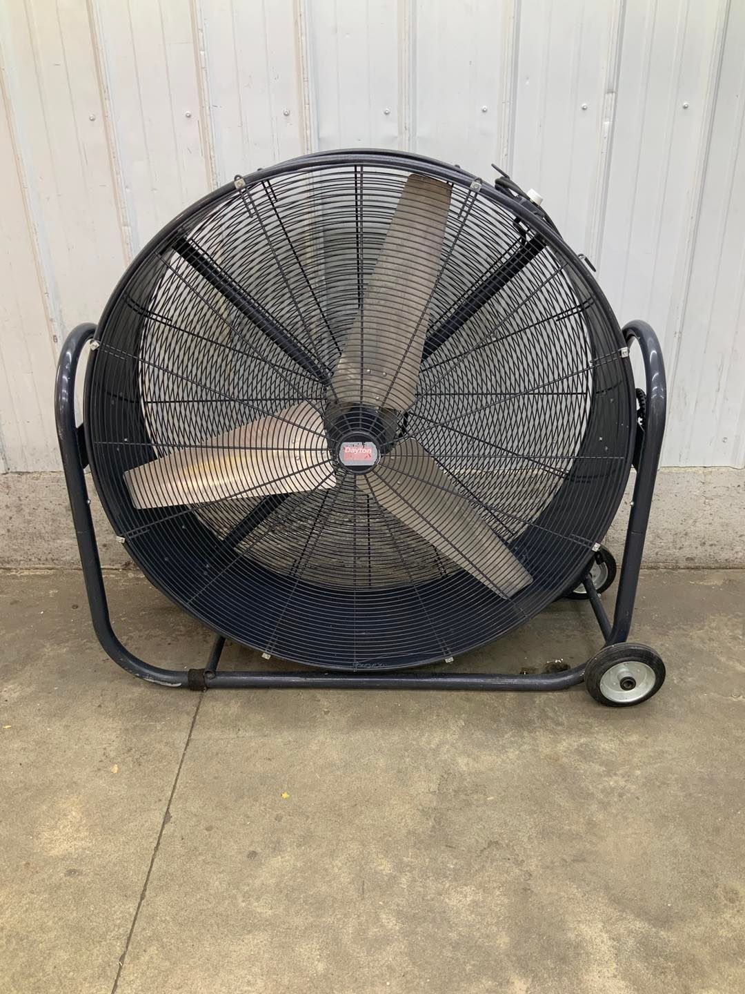 A large fan with wheels is sitting on the ground.
