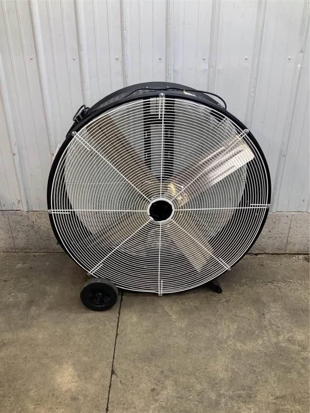 A large fan with wheels is sitting on the ground in front of a building.