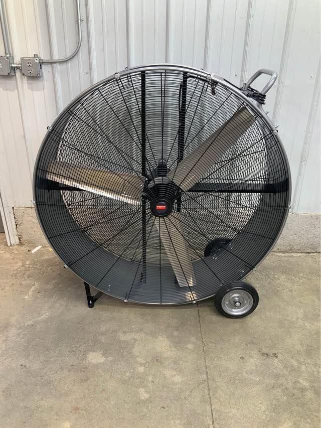 A large fan with wheels is sitting on the ground in front of a building.