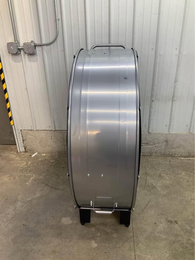 A large metal object is sitting on the ground in front of a building.