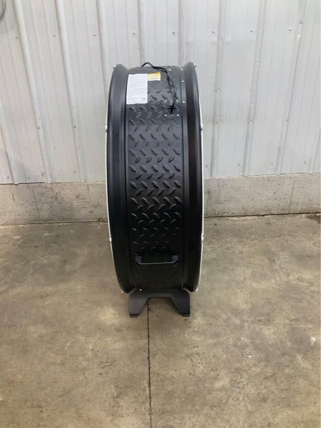 A black tire is sitting on a concrete floor next to a wall.