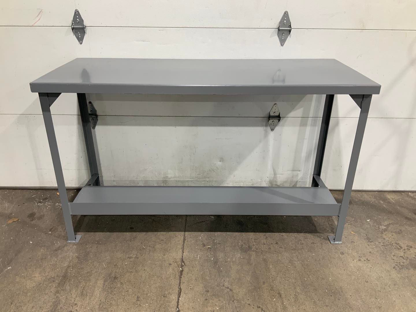 A gray metal table is sitting in front of a garage door.