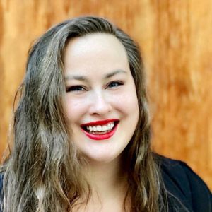 A woman with long hair and red lips is smiling for the camera.