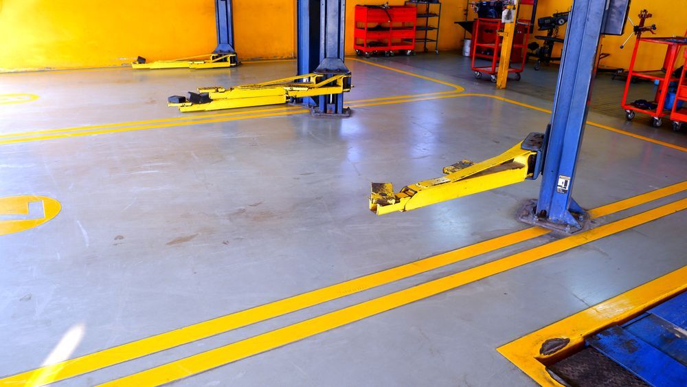 A garage with yellow lines on the floor and yellow lifts — Murphys Mobile Mechanical In Rockhampton, QLD