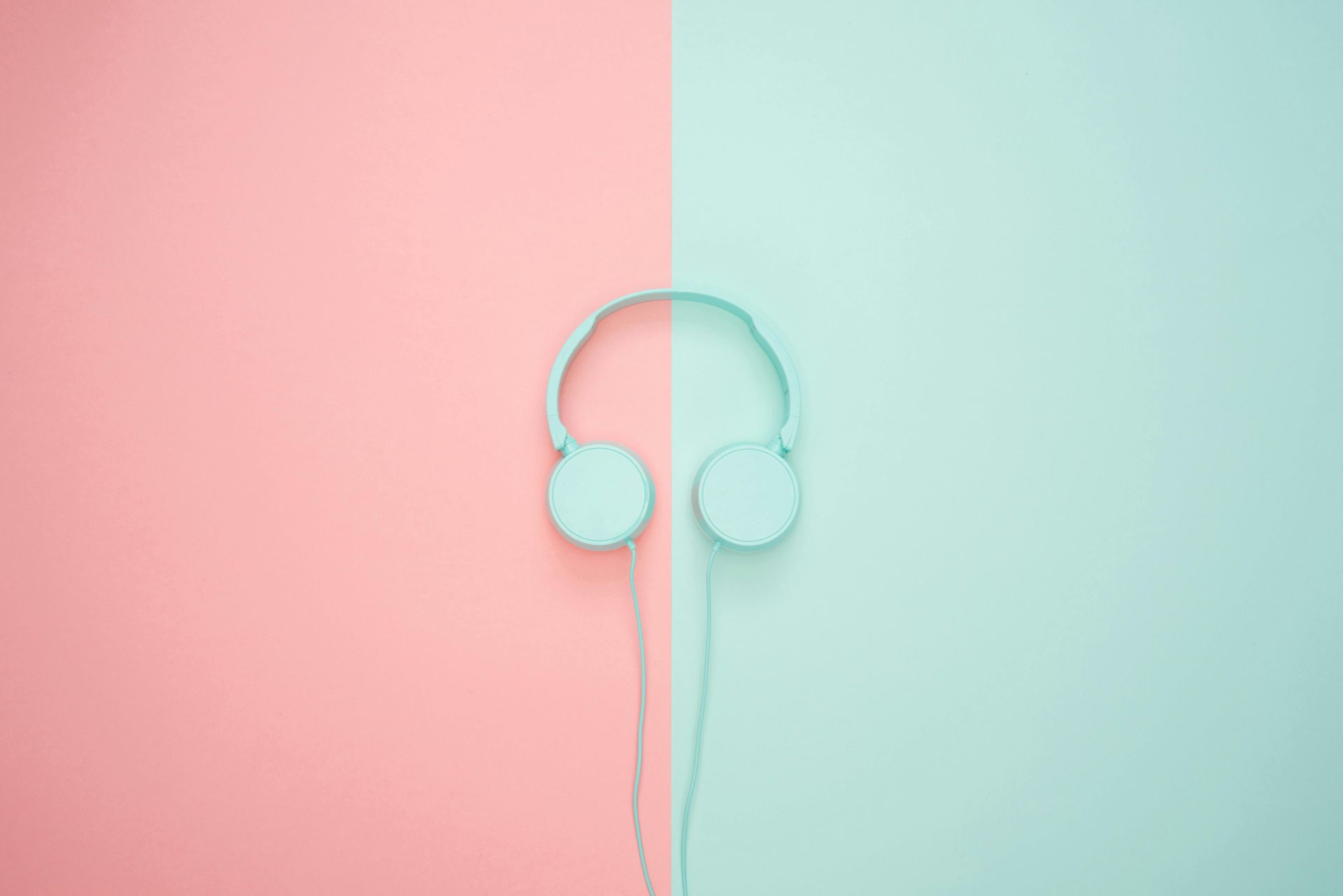 A pair of headphones on a pink and blue background.