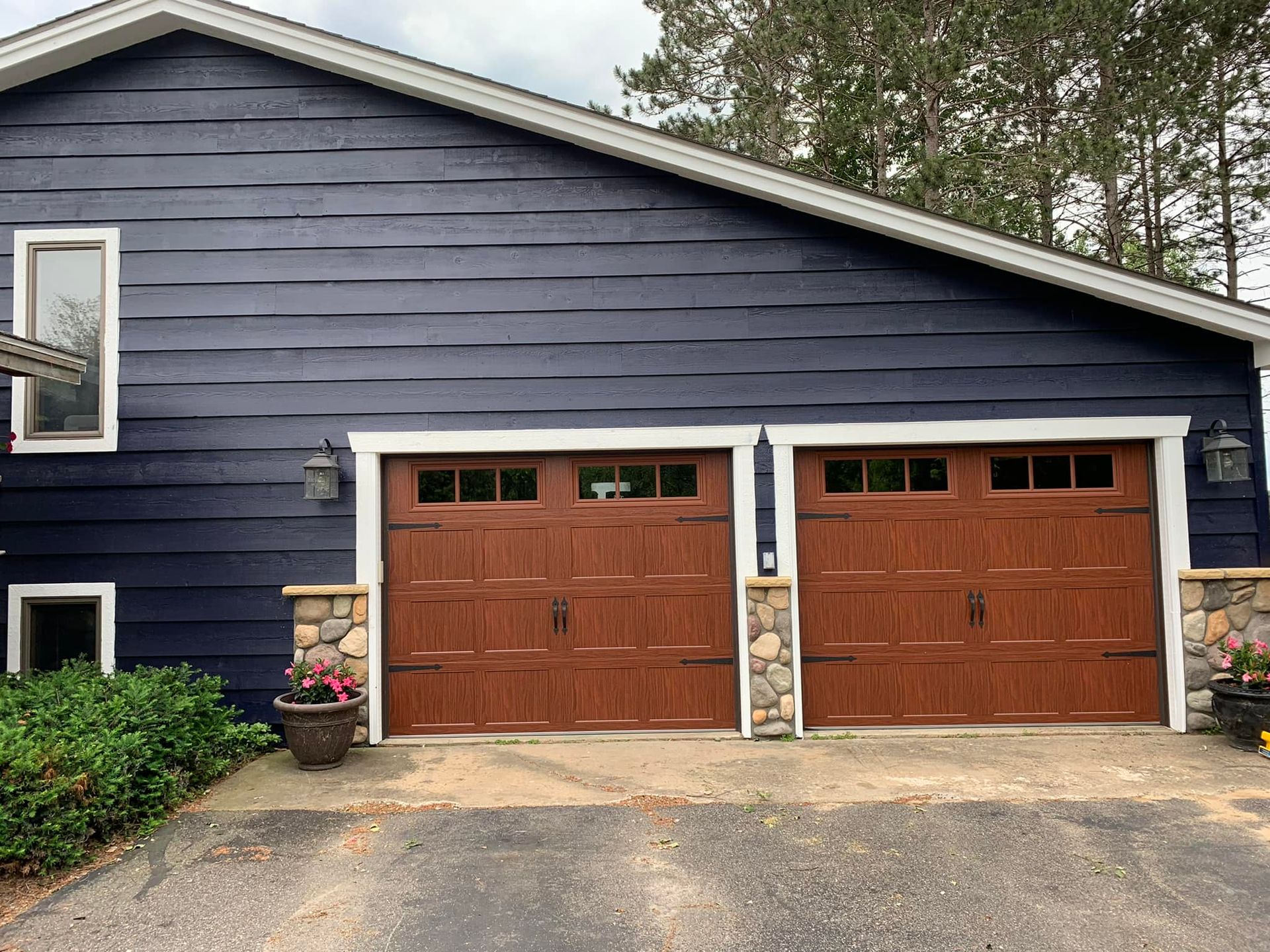 A blue house with two brown garage doors and a driveway.
