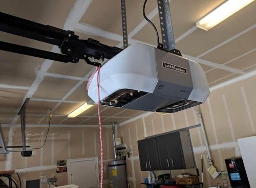 A garage door opener is hanging from the ceiling in a garage.