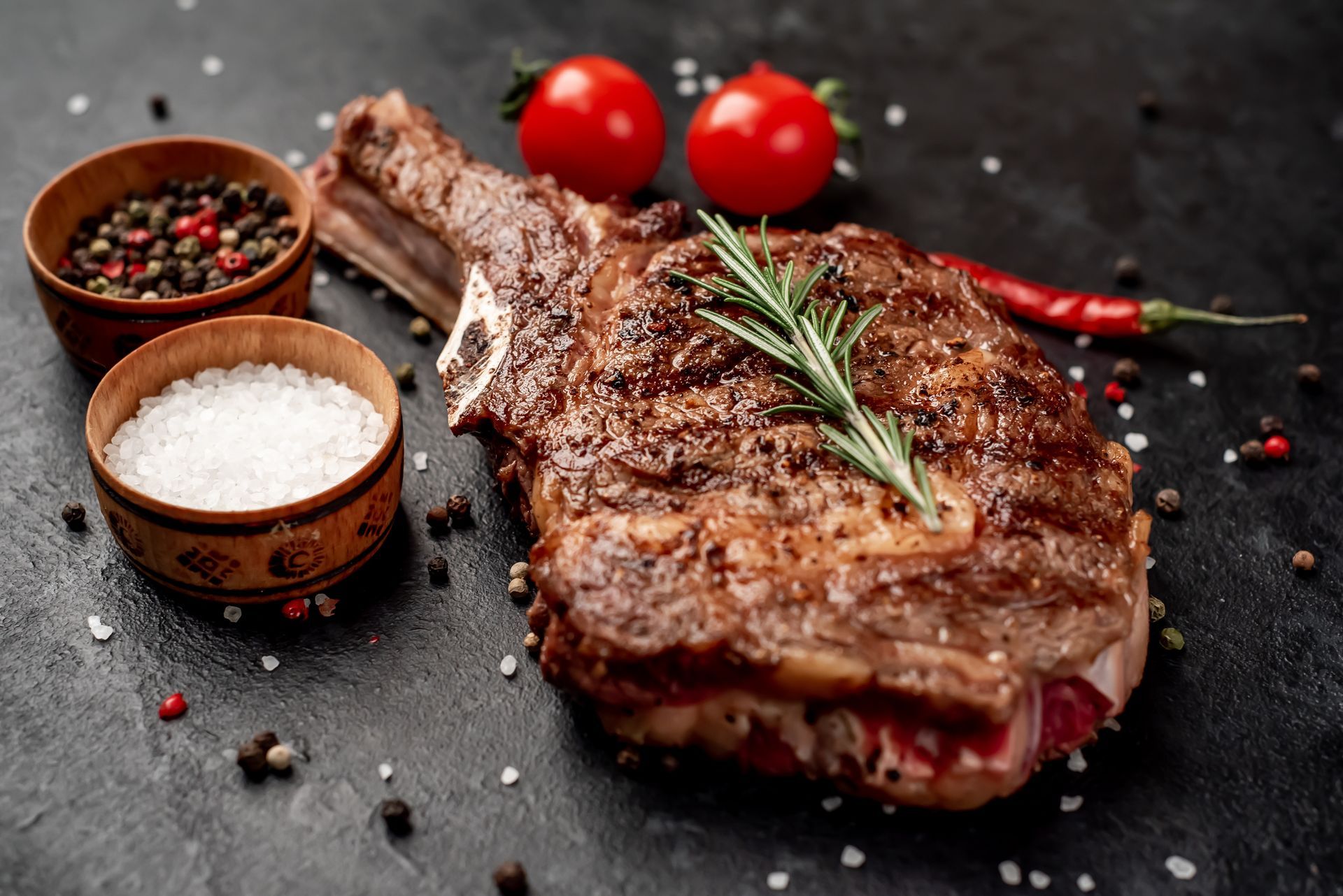 Un steak sur un os avec des tomates et des épices sur une table.