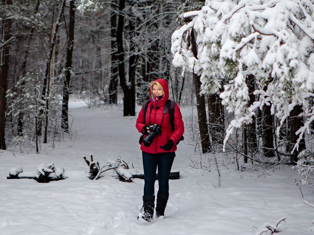 photographer walking in snowy wooded area