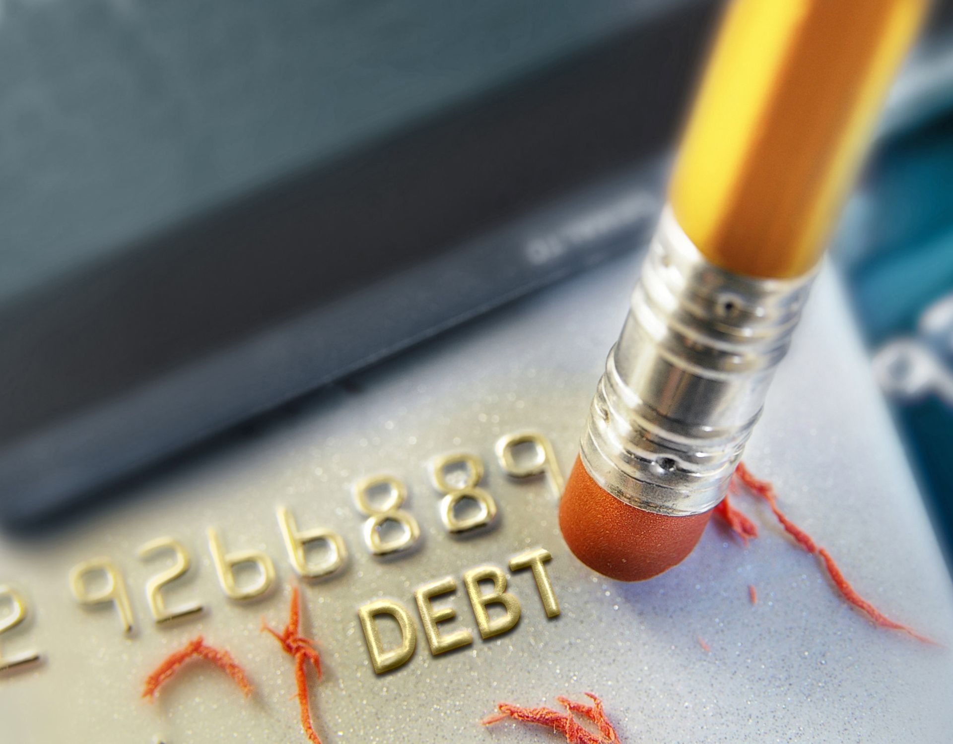 A pencil is erasing the word debt on a credit card