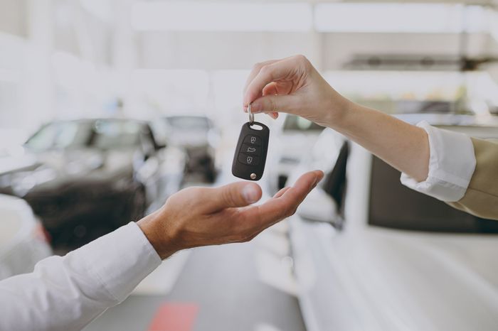 A man is handing a car key to a woman.