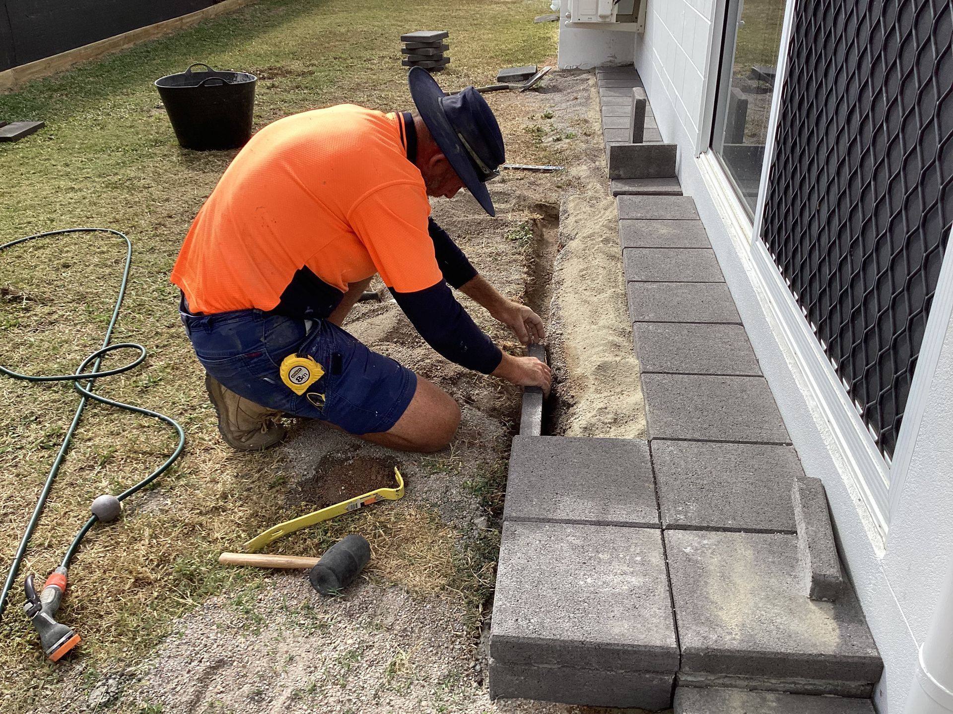 Mark is Using Tools to add the pavers— Handyman Services in Belgian Gardens, QLD