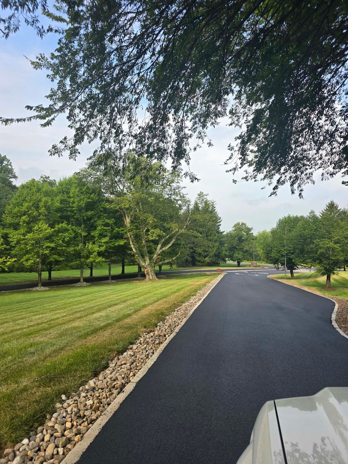 A car is parked on the side of a road surrounded by trees.
