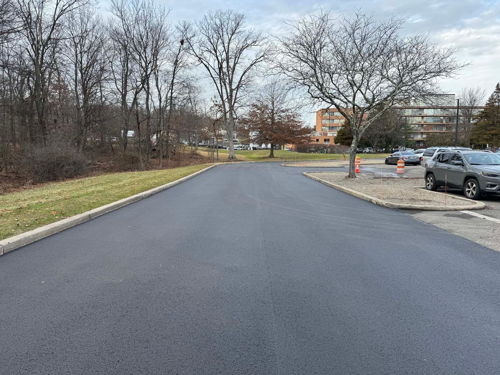 A newly paved road with cars parked on the side of it.