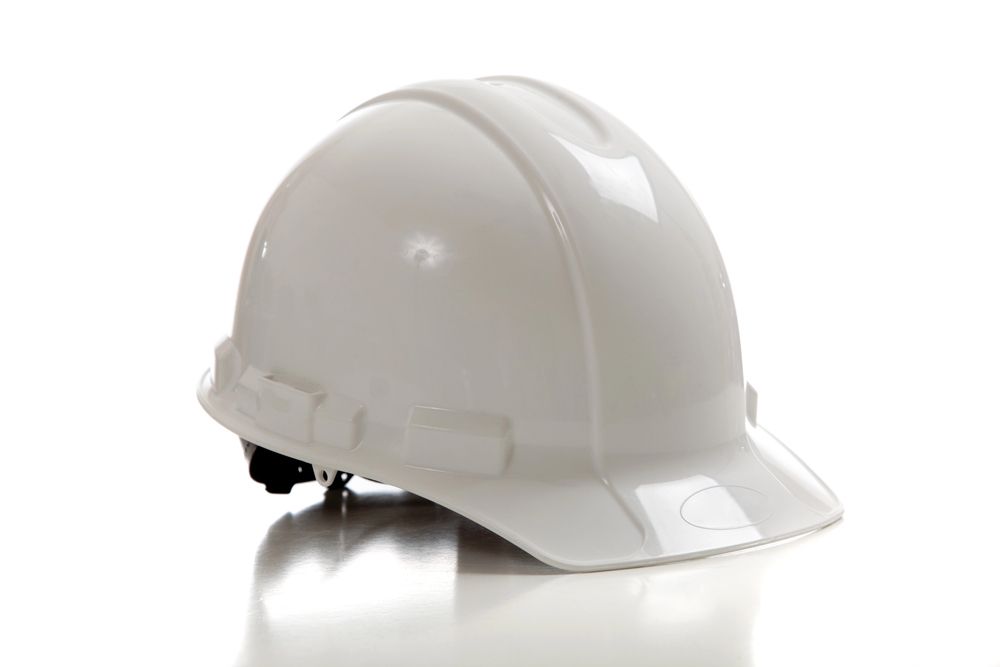 Casco blanco sobre superficie reflectante, de uso común para seguridad industrial o de construcción.