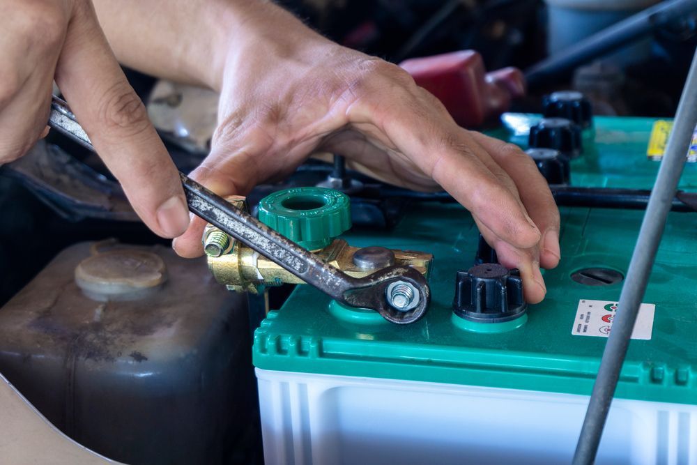 A Person is Plugging a Battery Into a Car With a Wrench — Central Coast Batteries In Long Jetty, NSW