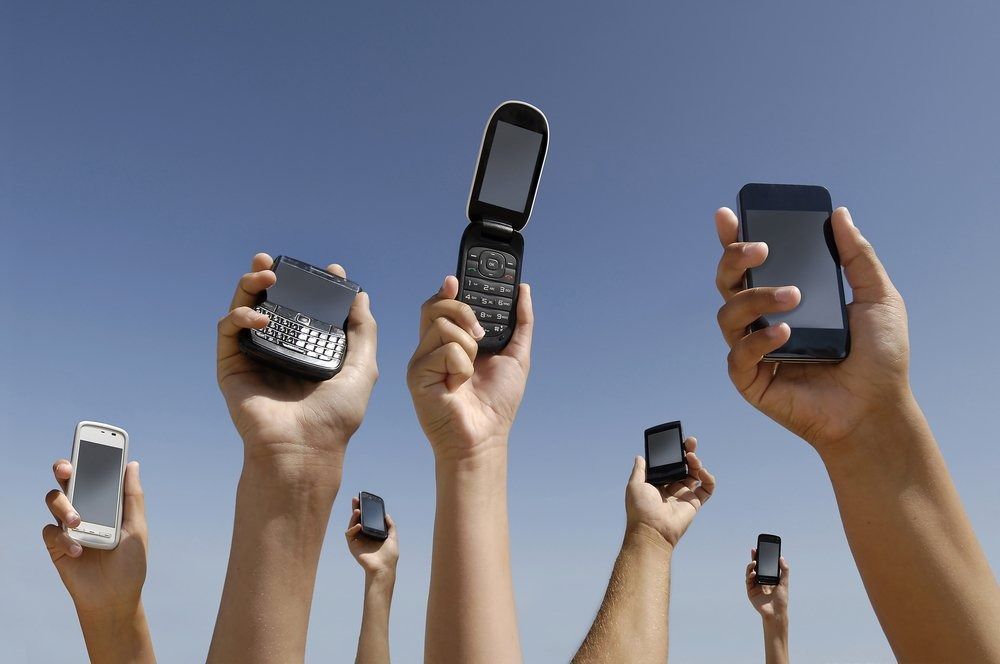 A Group of People Are Holding Up Their Cell Phones in the Air — Central Coast Batteries In Long Jetty, NSW