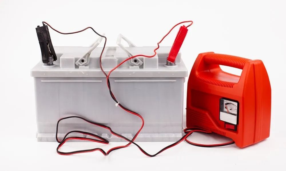 A Car Battery is Being Charged by a Red Charger — Central Coast Batteries In Long Jetty, NSW