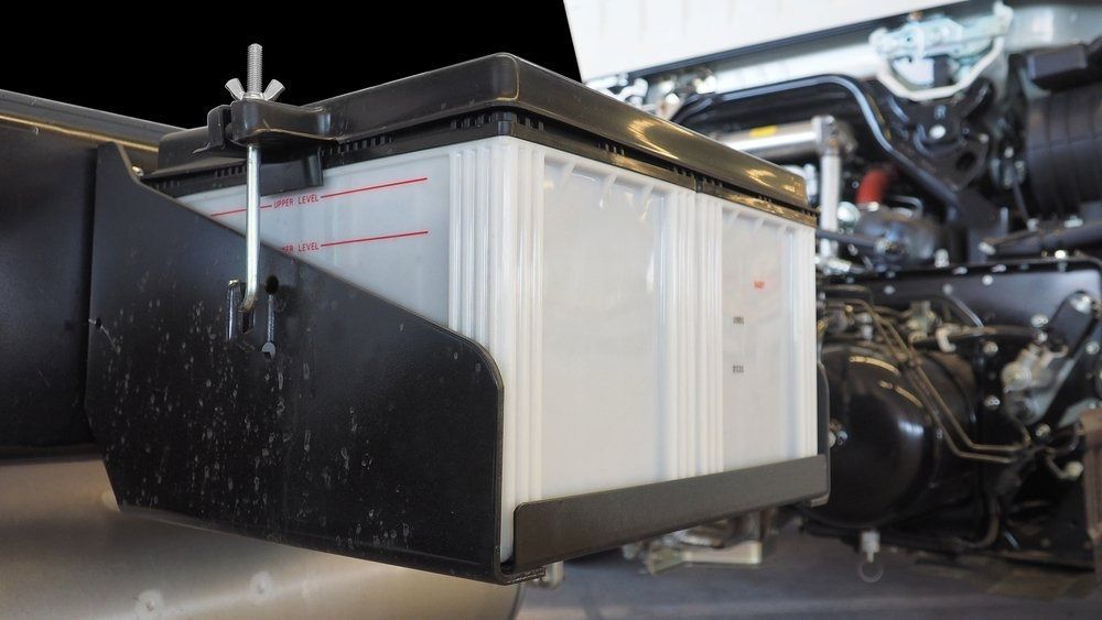 A Car Battery is Sitting Under the Hood of a Car — Central Coast Batteries In Long Jetty, NSW