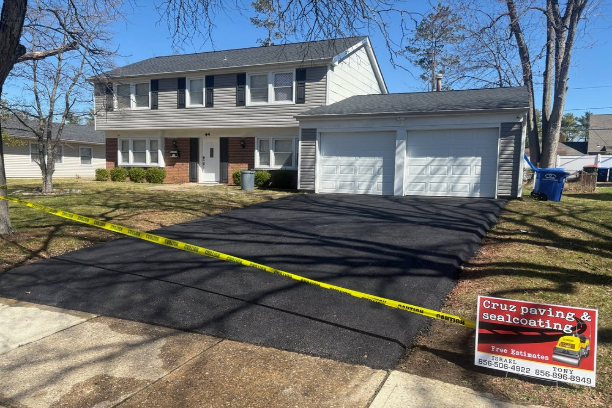 Two-story suburban house with a new asphalt driveway and double garage with a sign in front that says