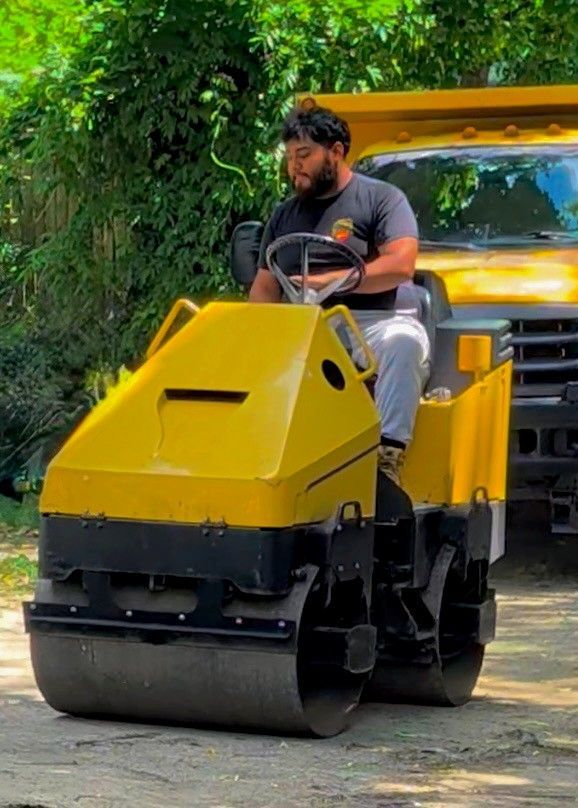 Israel Cruz, owner of Cruz Paving & Sealcoating sitting on yellow paving compactor machine
