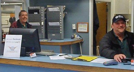 two men are sitting at a counter in a auto sho