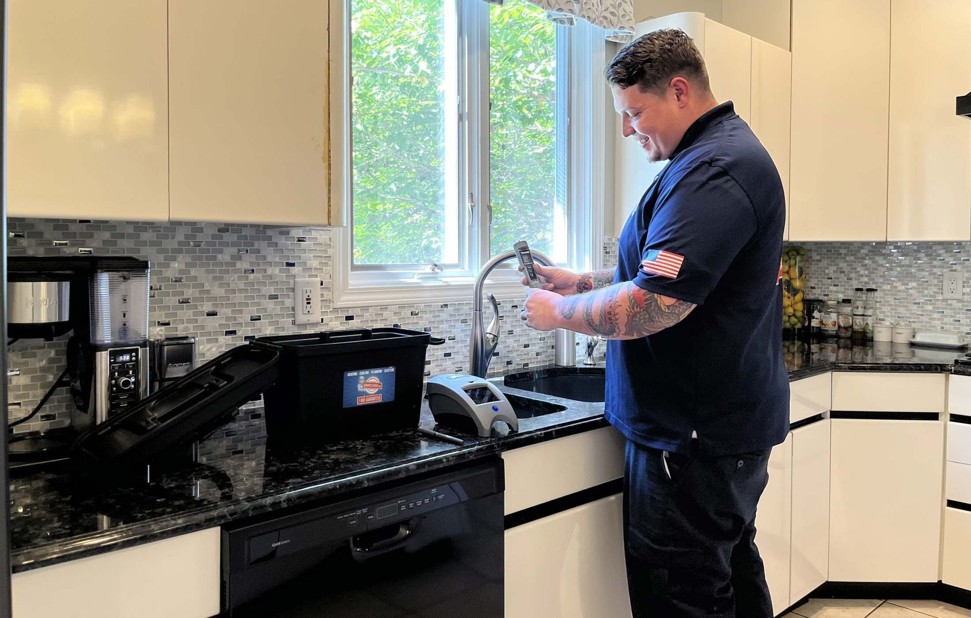 A man is standing in a kitchen looking at a hose.