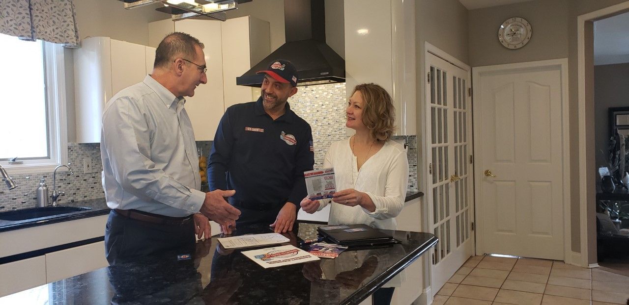 A man and a woman are standing in a kitchen talking to each other.