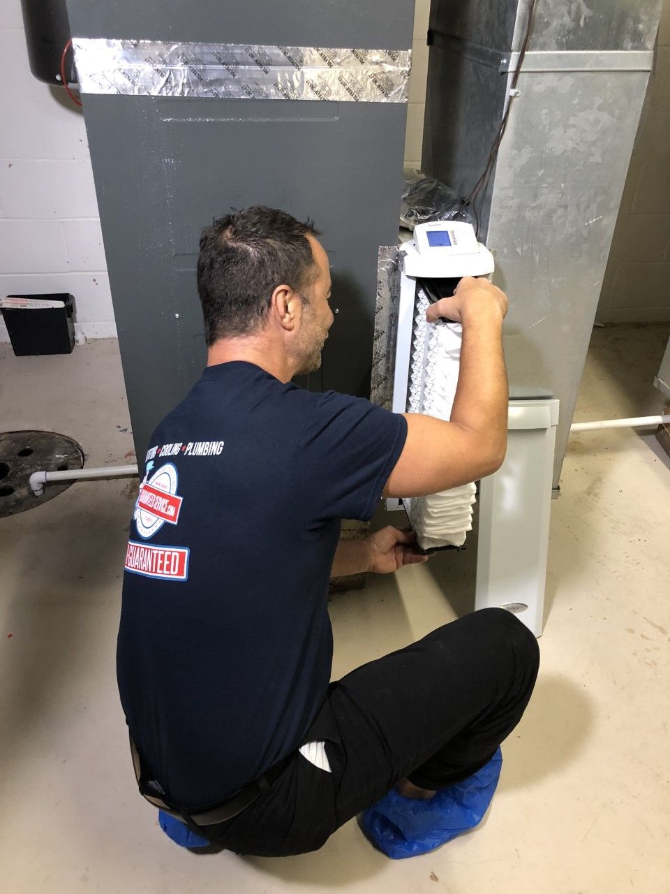 A man in a blue shirt is working on an air conditioner.