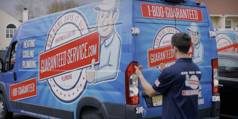 A man is standing in front of a guaranteed service van.