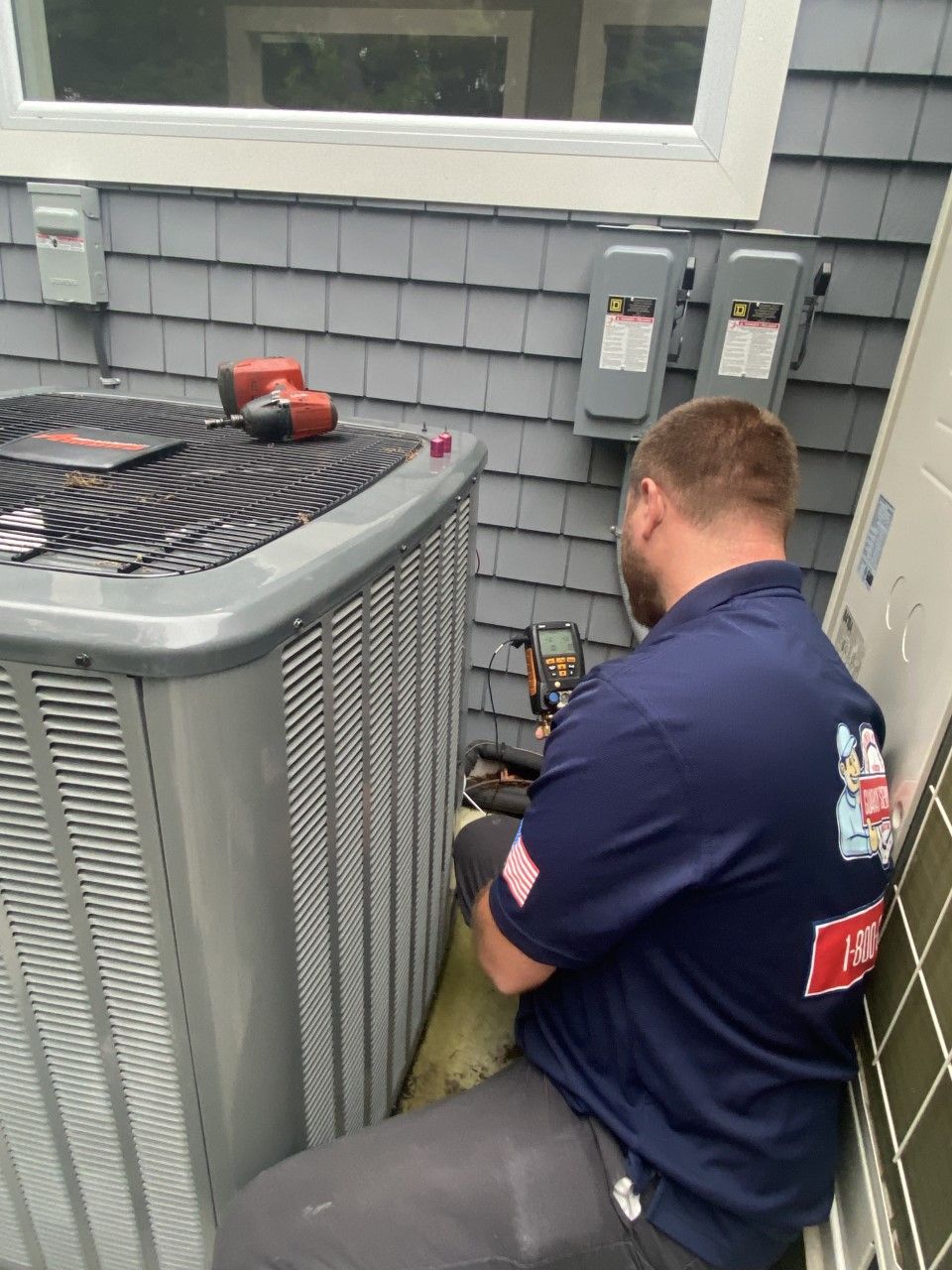 A man is working on an air conditioner outside of a house.