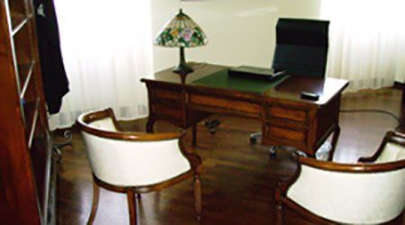 una scrivania in legno con due sedie e una poltrona nera