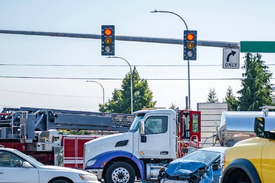 Car and truck accident at intersection with fire truck in background. 