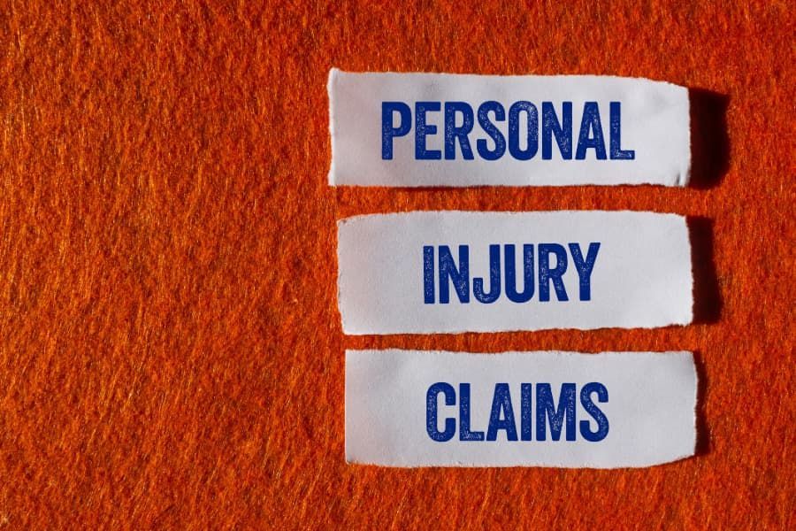 The words “personal injury claims” written on three torn pieces of paper with an orange background.