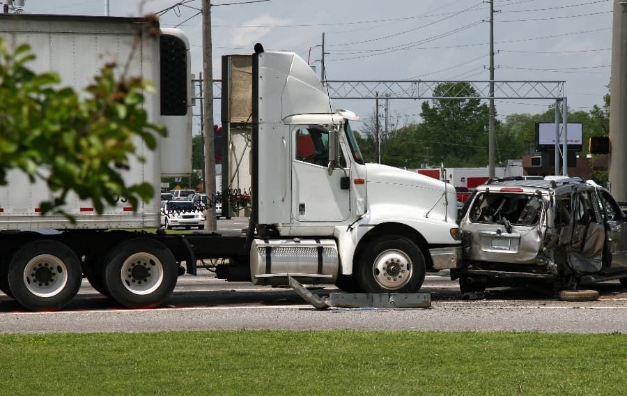 Tractor-trailer and smashed silver car after an accident