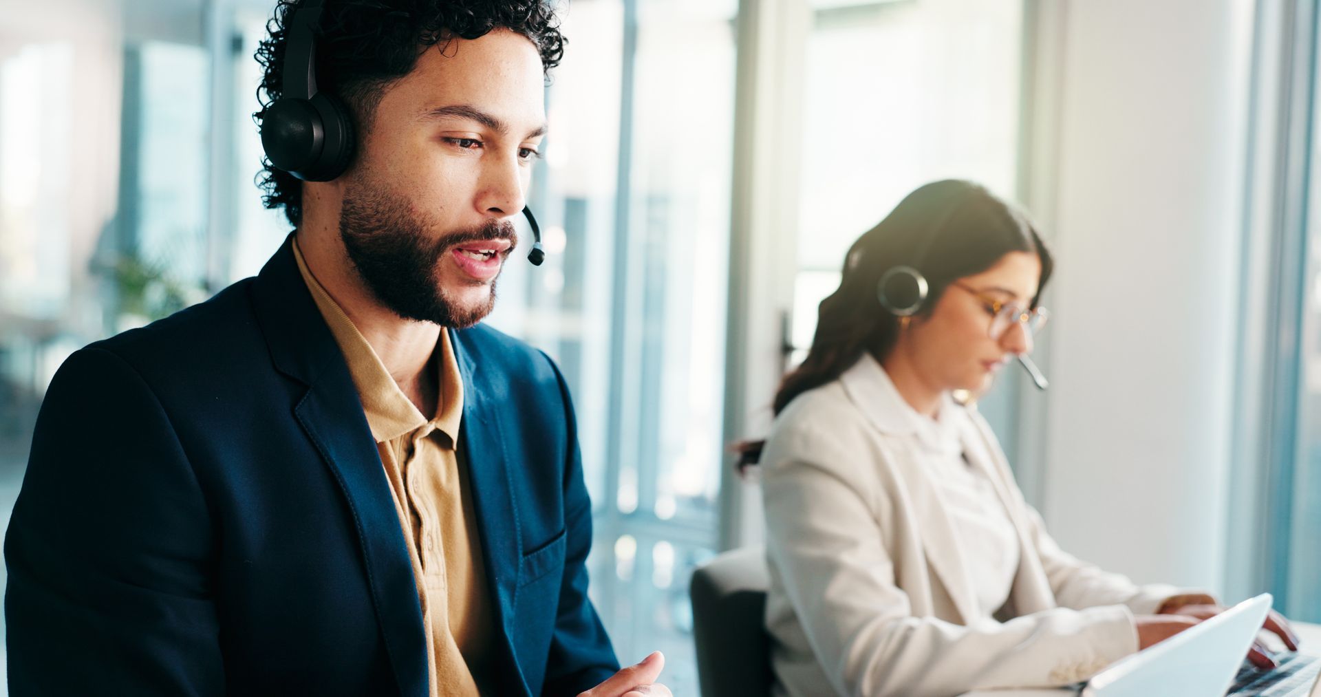 Call center staff working at desks with headsets in a bright office environment. Call center staff working at desks with headsets in a bright office environment.