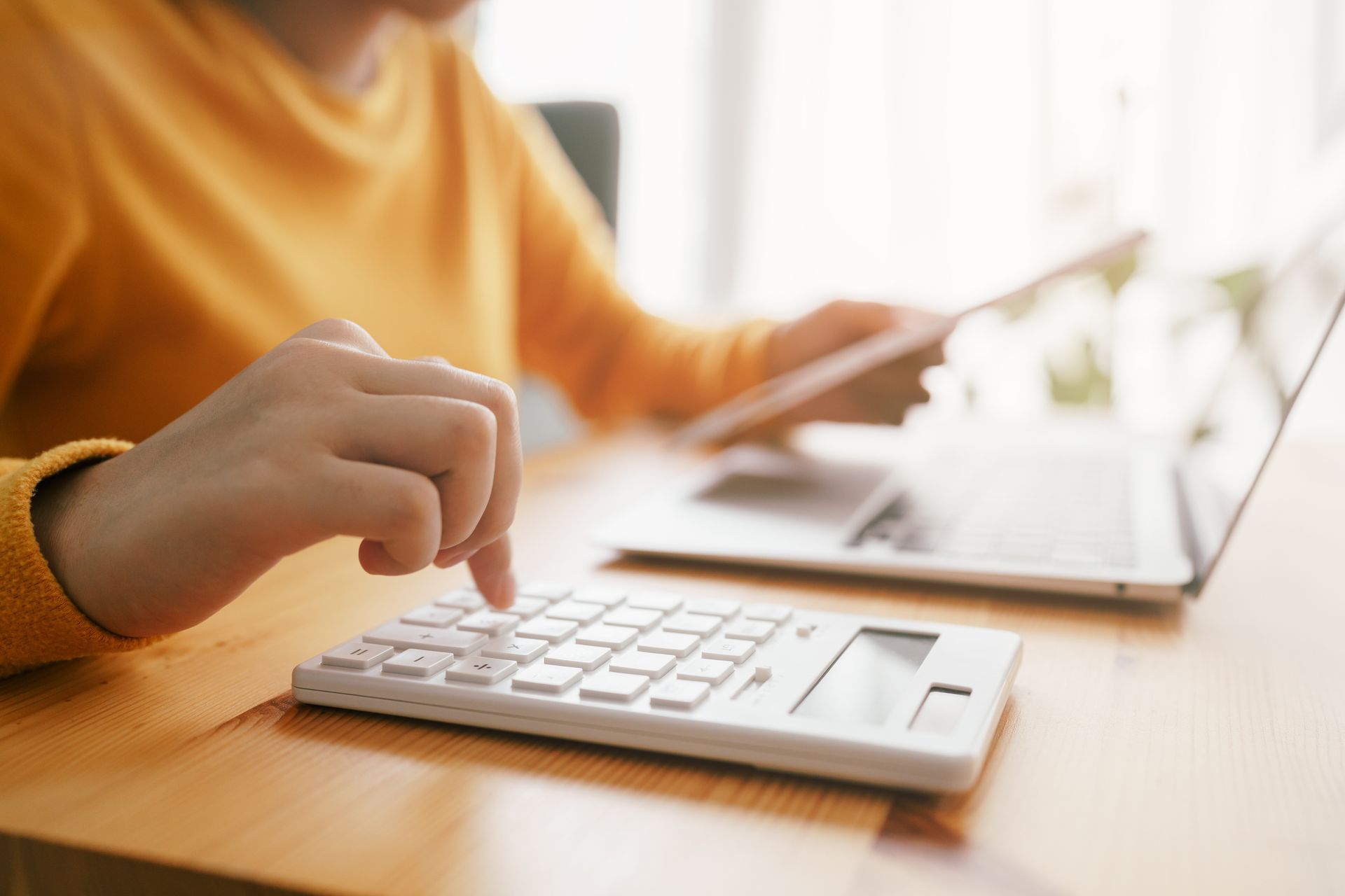 Close-up of a woman’s hand as she types on a calculator.