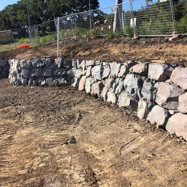 A Stone Wall Is Being Built on Top of A Dirt Hill — Webster Rock Walls In Caloundra, QLD