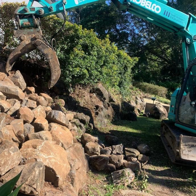 A Kobelco Excavator Is Working on A Pile of Rocks — Webster Rock Walls In Caloundra, QLD