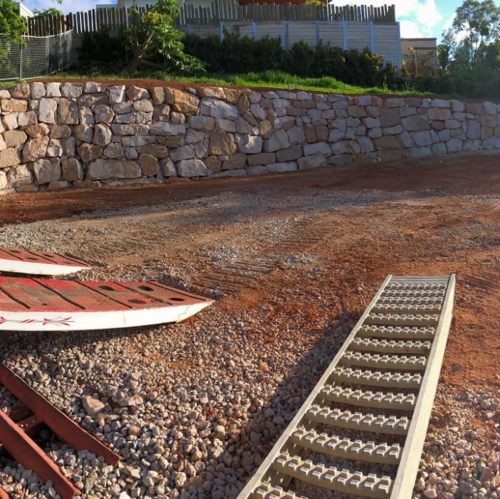 A Metal Ramp Sits in The Dirt Next to A Boat Ramp — Webster Rock Walls In Ilkley, QLD