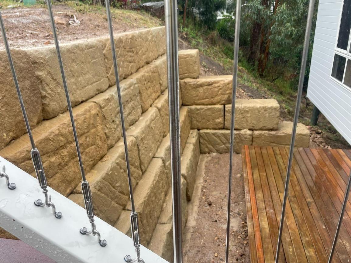 A View of A Stone Wall and A Wooden Deck from A Balcony — Webster Rock Walls In Noosa, QLD